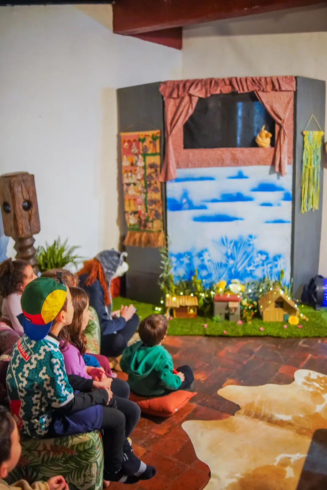 Crianças sentadas assistindo ao teatro de fantoches no salão da fazenda