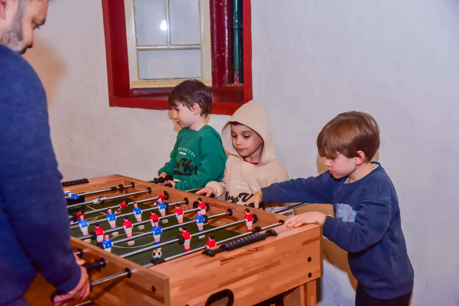 Crianças jogando pebolim no salão de jogos