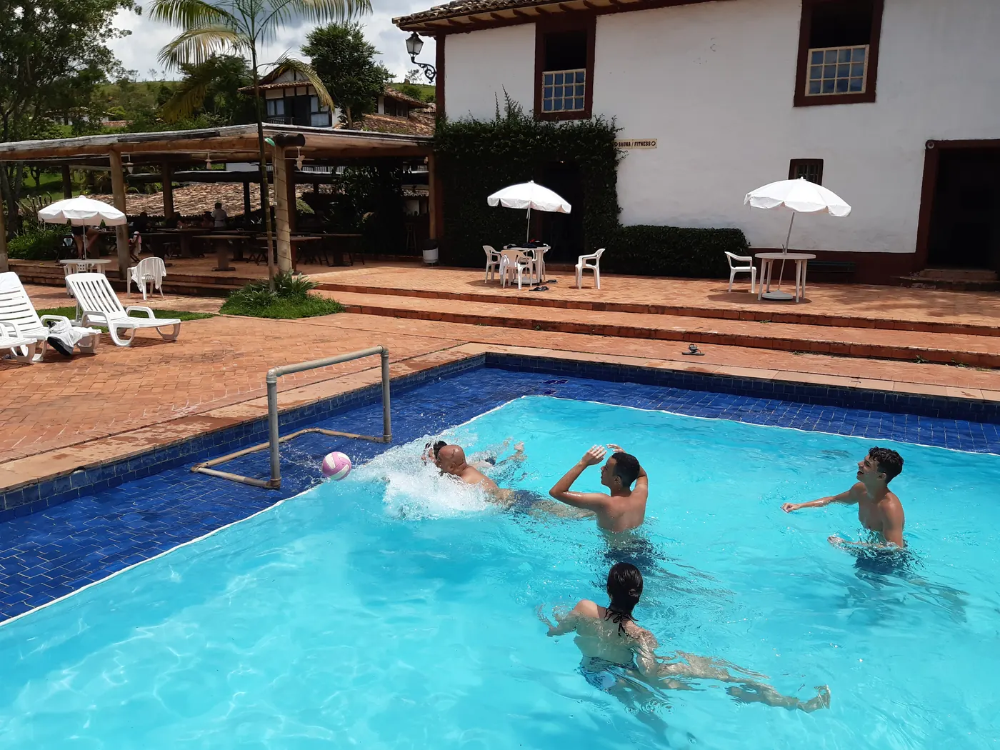 Hóspedes brincando na piscina em frente ao casarão
