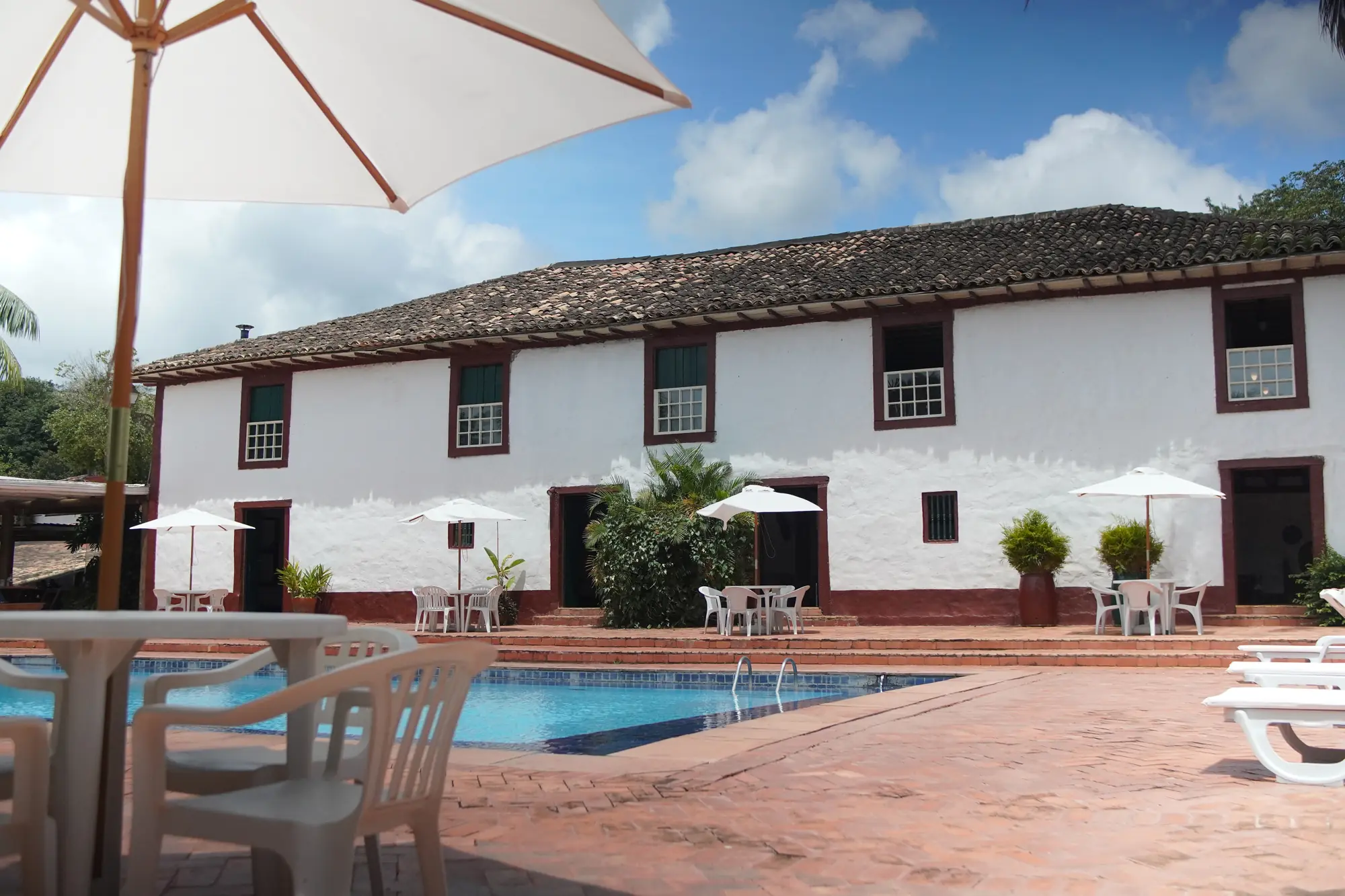 Casarão colonial com a piscina e os guarda-sóis em frente