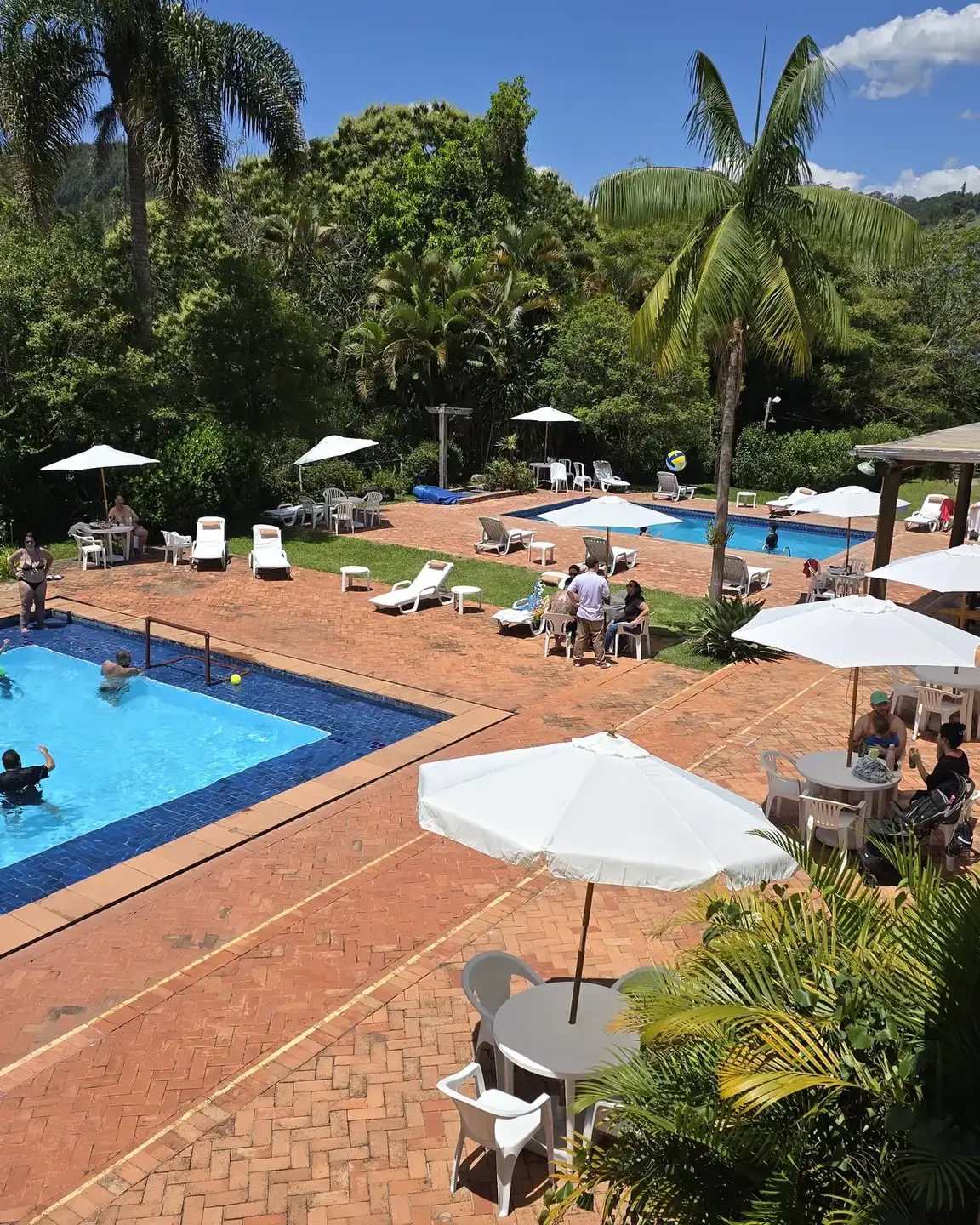 Piscinas, guarda-sóis e palmeiras da área comum do Hotel Fazendão vistos do alto