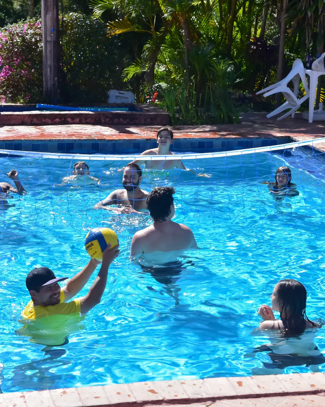 Vôlei na piscina com o monitor de recreação em dia de sol